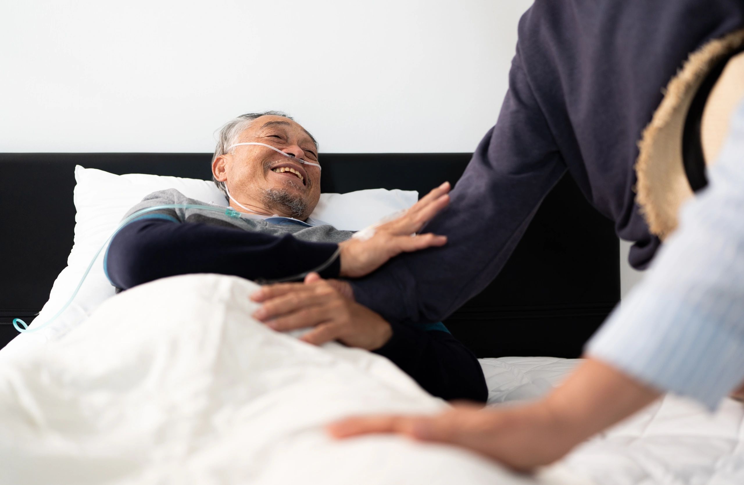 Elderly man in hospital bed with caregiver